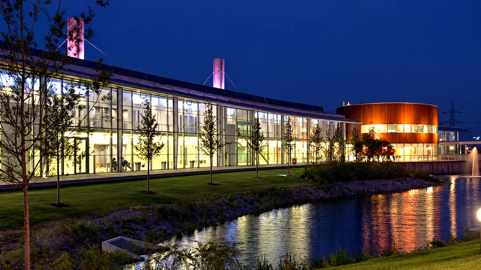 Illuminated campus buildings reflected in the lake at dusk